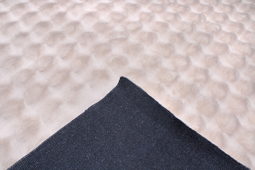 Close up view of cream faux fur rug backing
