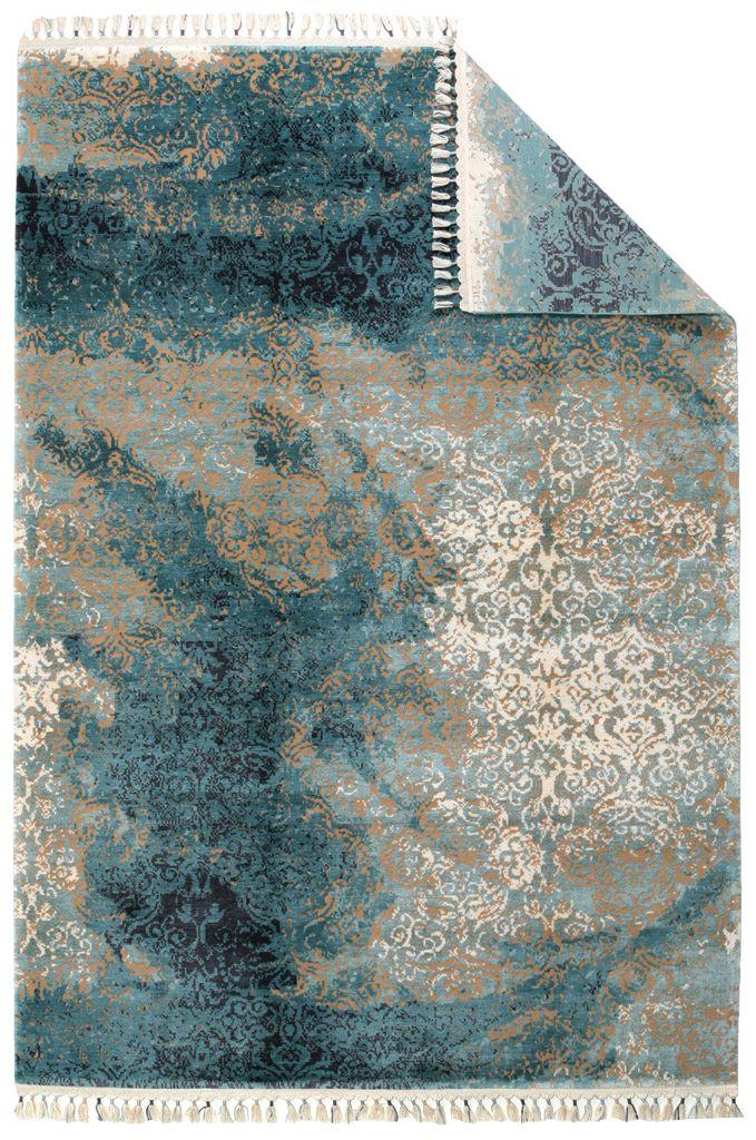 Overhead view of teal, beige, white abstract patterned rug with tassels