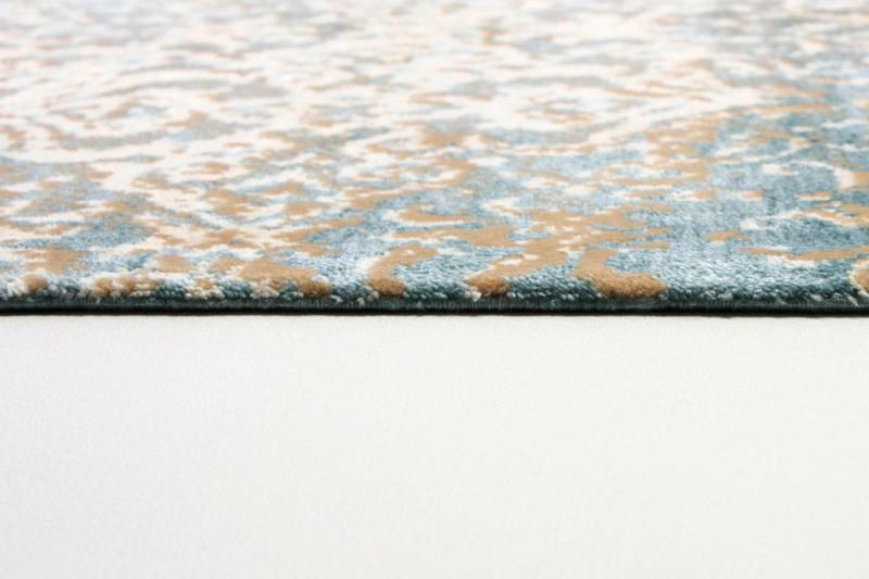 Close up view of blue, white, tan patterned rug edge