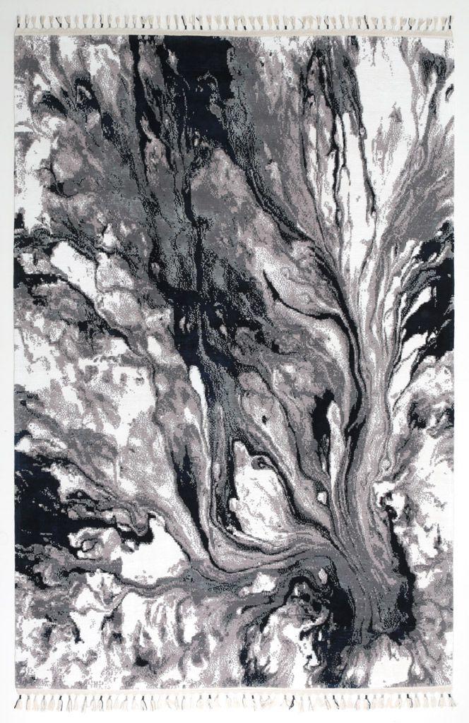 Overhead view of gray, black, white abstract patterned rug with tassels