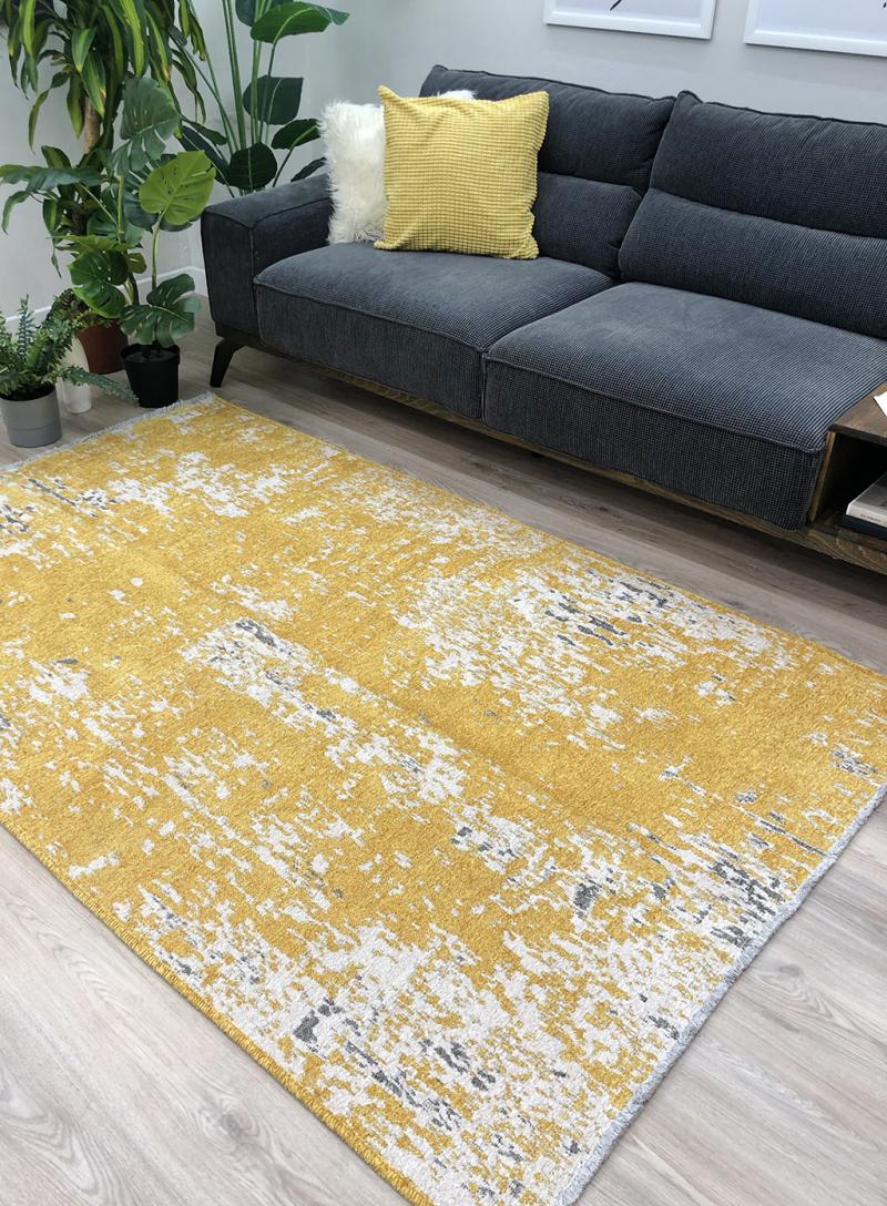 Yellow abstract area rug on light wood floor beside sofa