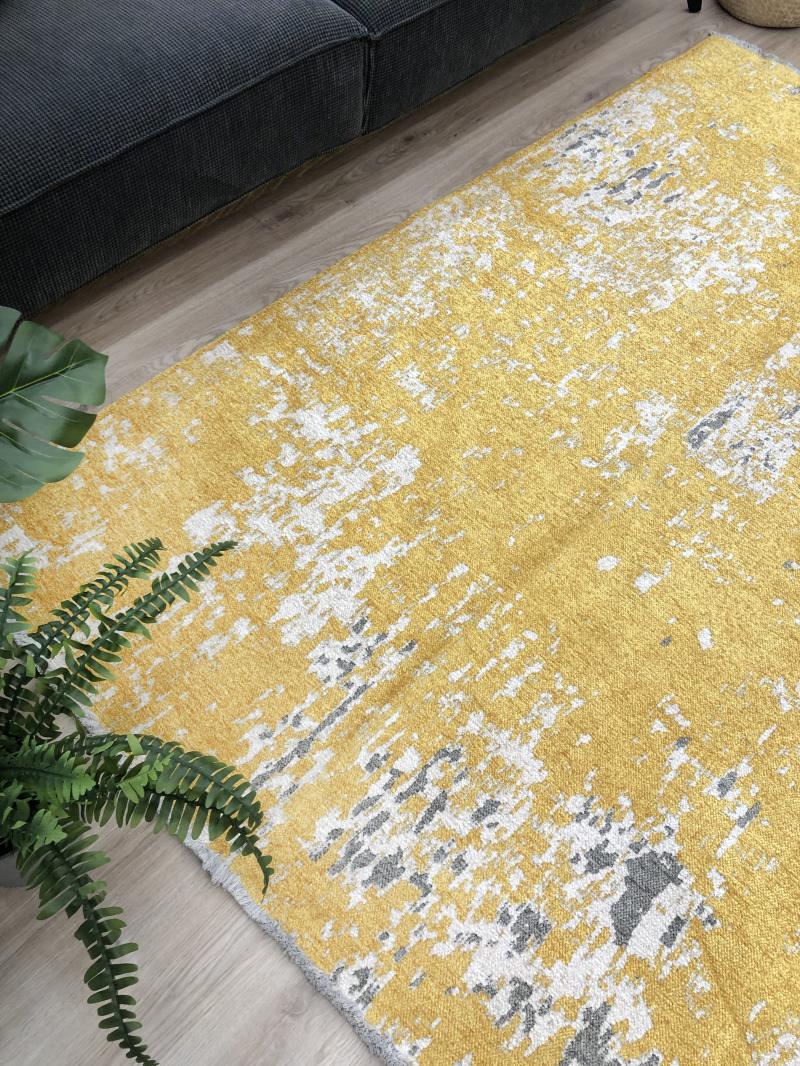 Overhead view of yellow abstract patterned area rug on wood floor