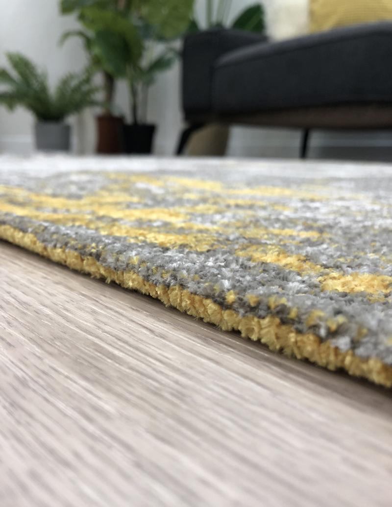 Close up gray yellow abstract pattern area rug on wood floor