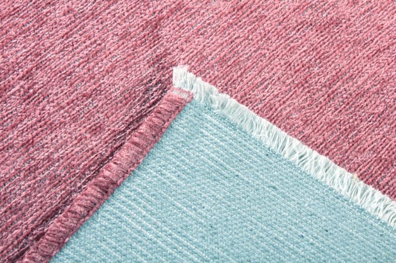 Close up view of pink rug top and light blue backing