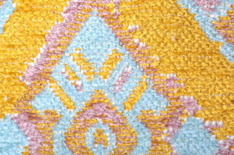 Close up view of yellow, pink, blue patterned rug texture