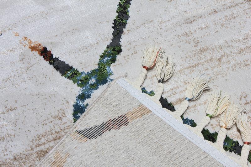 Close up of abstract patterned rug with tassels and backing visible