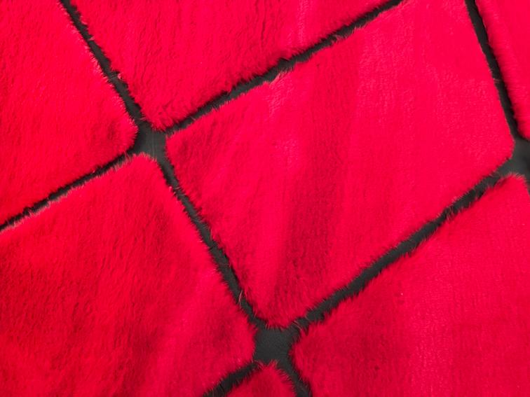 Rabbit Fur Rug placed in a chic bedroom, adding drama and sophistication with its red and black hues.