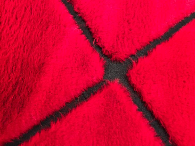 Rabbit Fur Rug placed in a chic bedroom, adding drama and sophistication with its red and black hues.