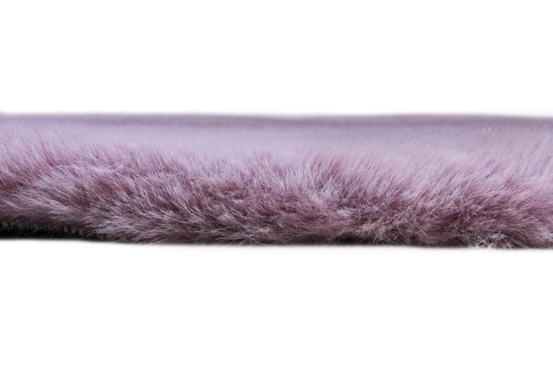 Angled view of Rabbit Round Fur Rug under a stylish chair, highlighting its sophisticated design in a cozy space.