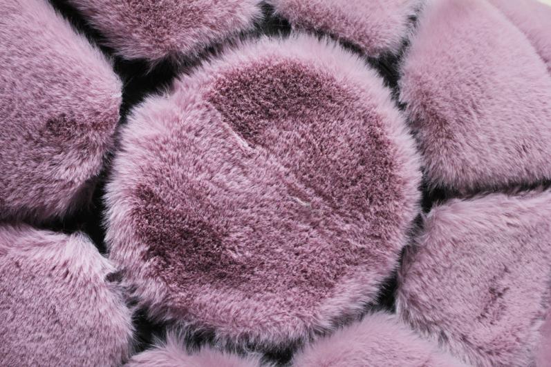 Rabbit Round Fur Rug placed in a chic bedroom, adding a touch of sophistication with its rose and black hues.