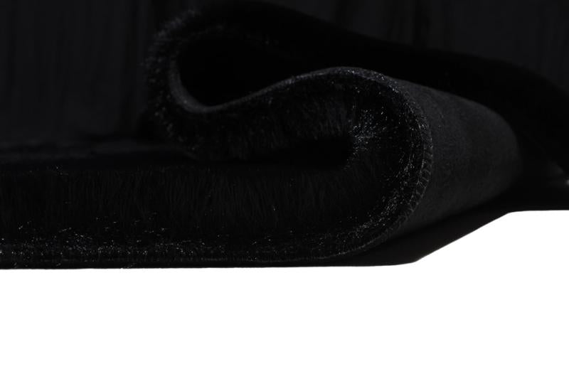 Black sheep-textured rabbit fur rug placed in a contemporary living room, enhancing the space with its unique design.