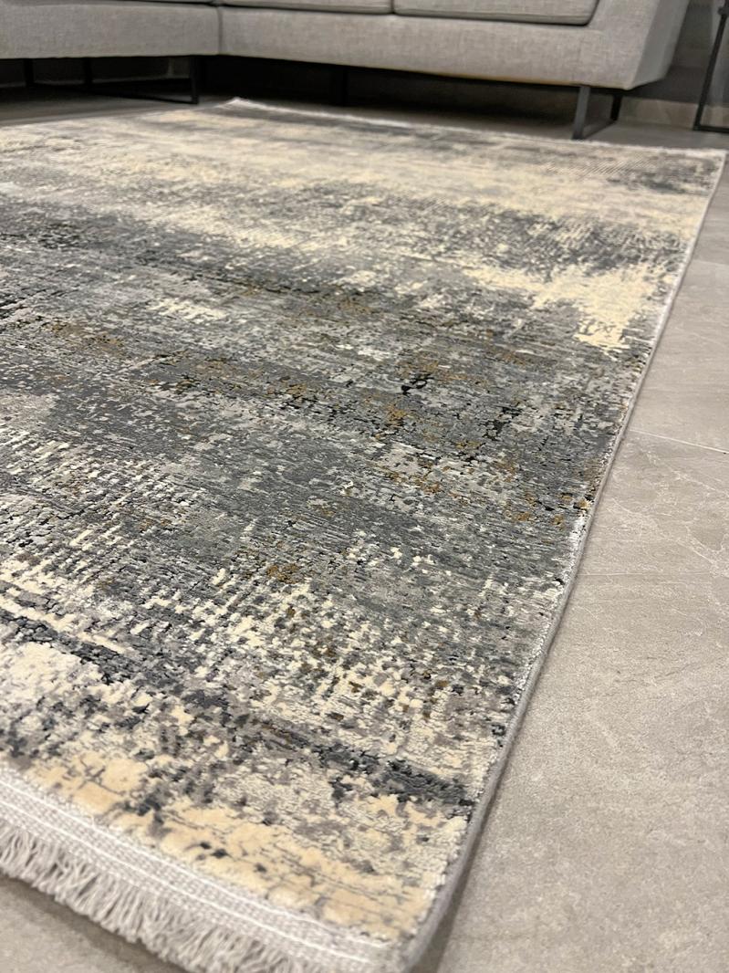 View of abstract gray and cream area rug with fringe.