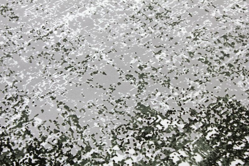 Close up view of gray and dark green abstract patterned rug