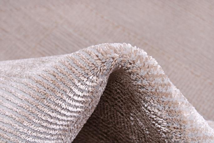 Close-up of the Infiniti Rug's texture, emphasizing its soft fibers and neutral beige palette that complements various decors.
