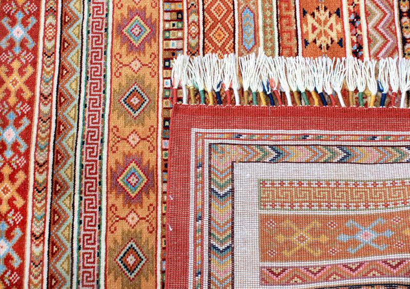 Close-up of a Zara handwoven rug with vibrant geometric patterns, warm tones, and fringe detail. Perfect for adding ethnic style to your home decor