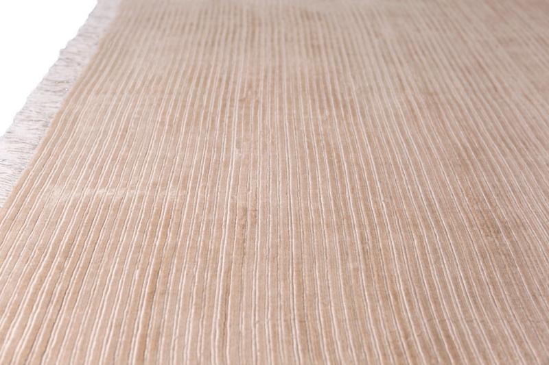 Close up view of beige striped rug with fringe