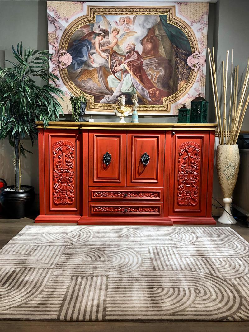 Interior with a red Luzione sideboard cabinet featuring ornate carvings and a modern patterned Luzione 906 Trace Tufted Rug
