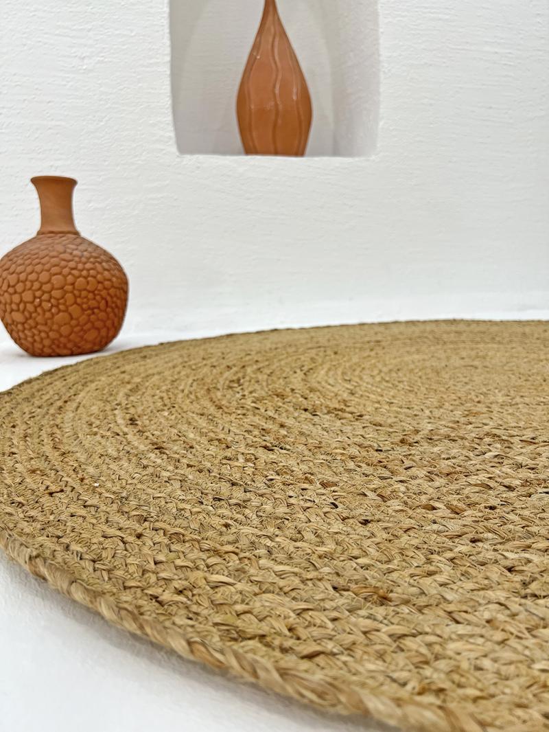 Close up view of round jute rug and terracotta vases