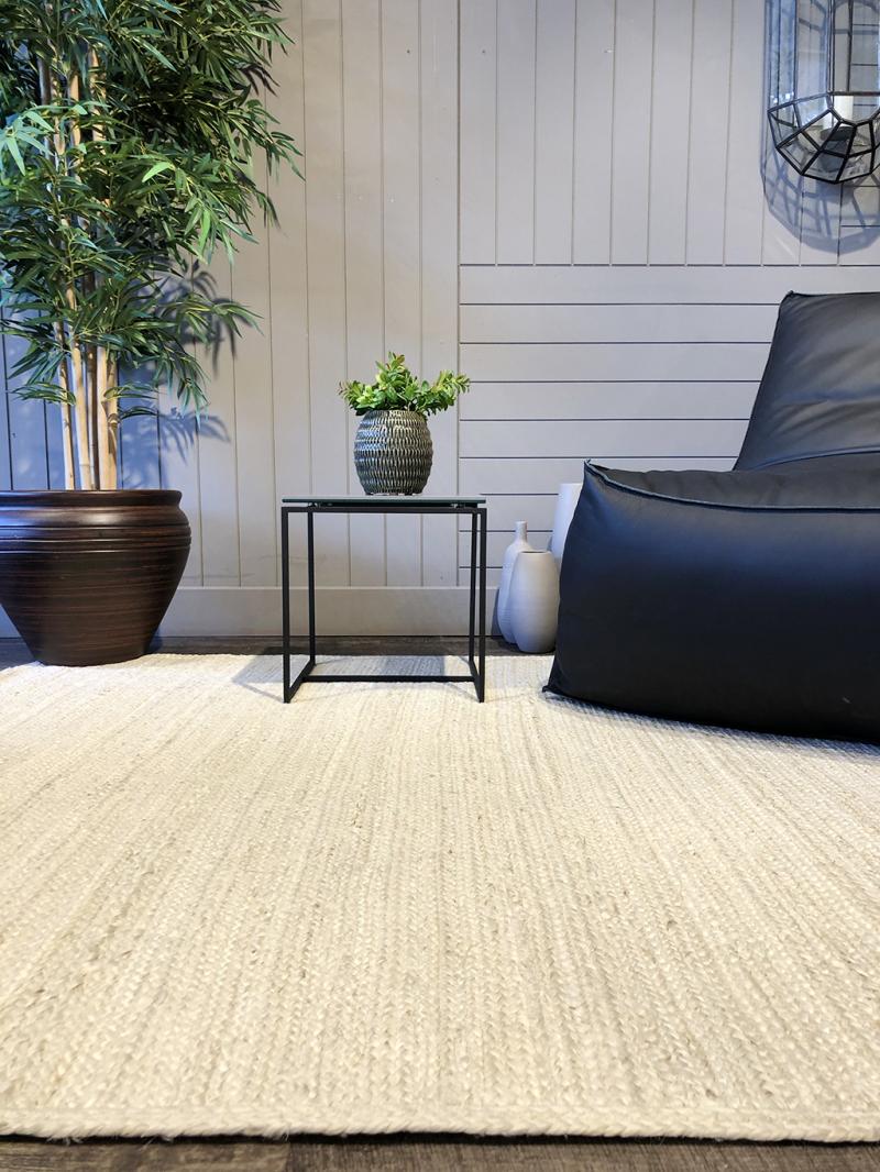 Luzione 910 Urban Rug: Jute rug, black beanbag chair, side table, potted plant create a cozy, modern living room interior.