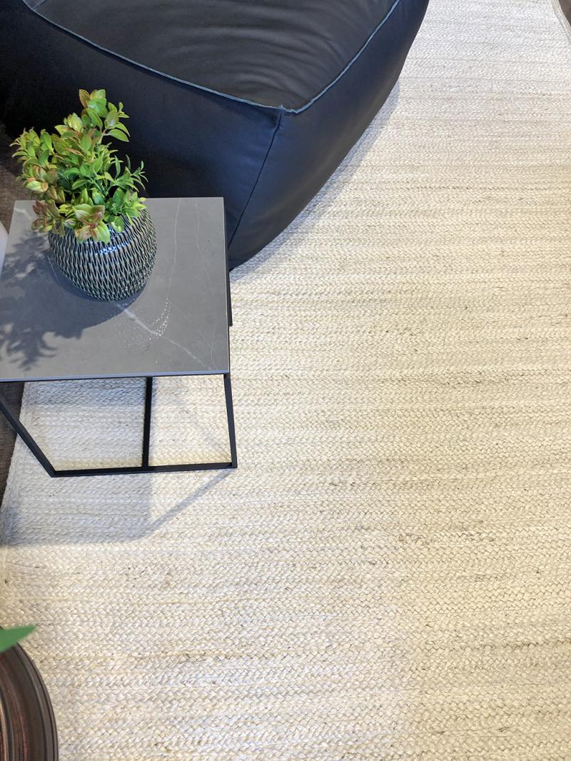 Modern living room featuring a Luzione black leather beanbag chair, marble top side table, and a textured 910 Urban jute rug