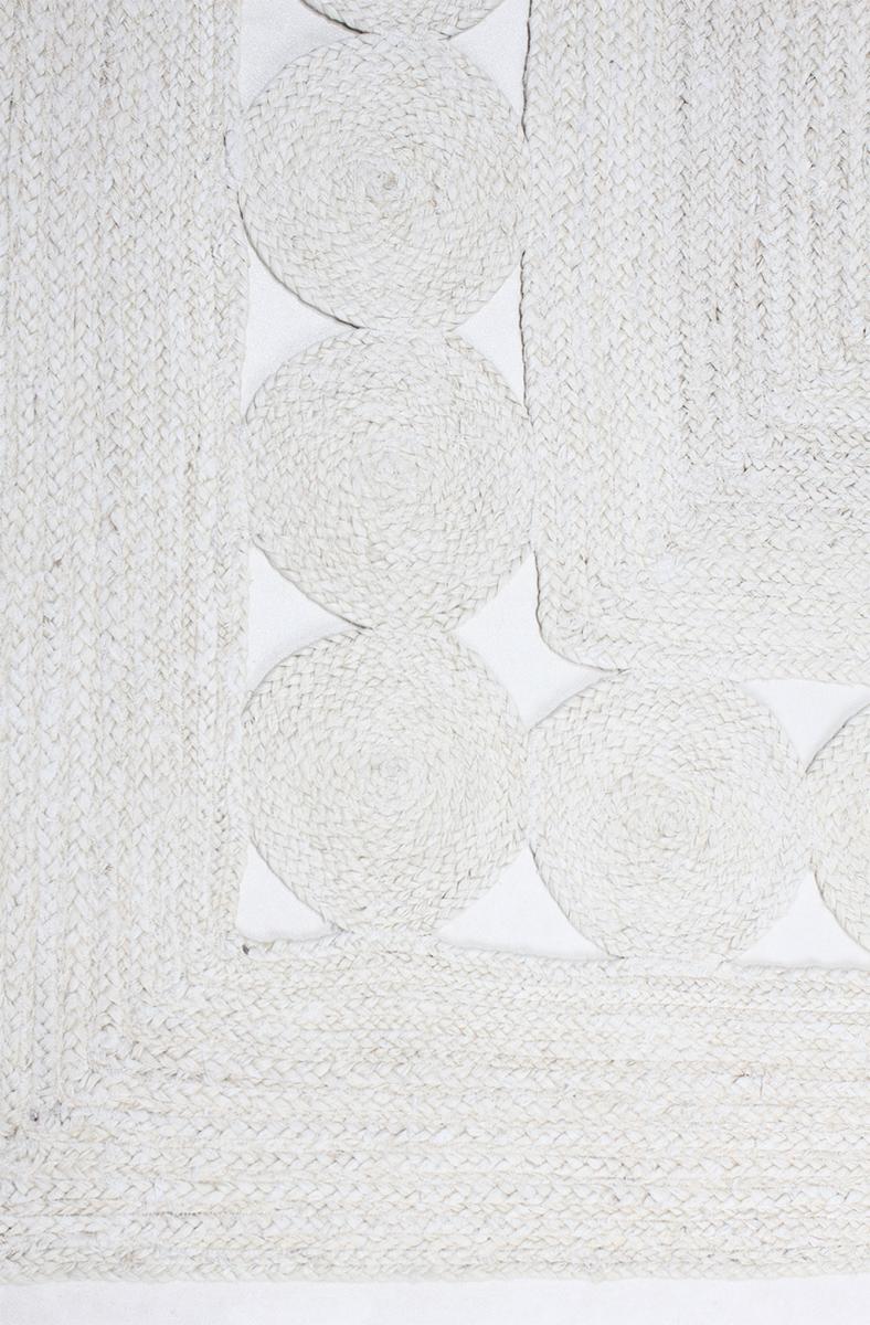 Close up white braided jute rug with circular patterns