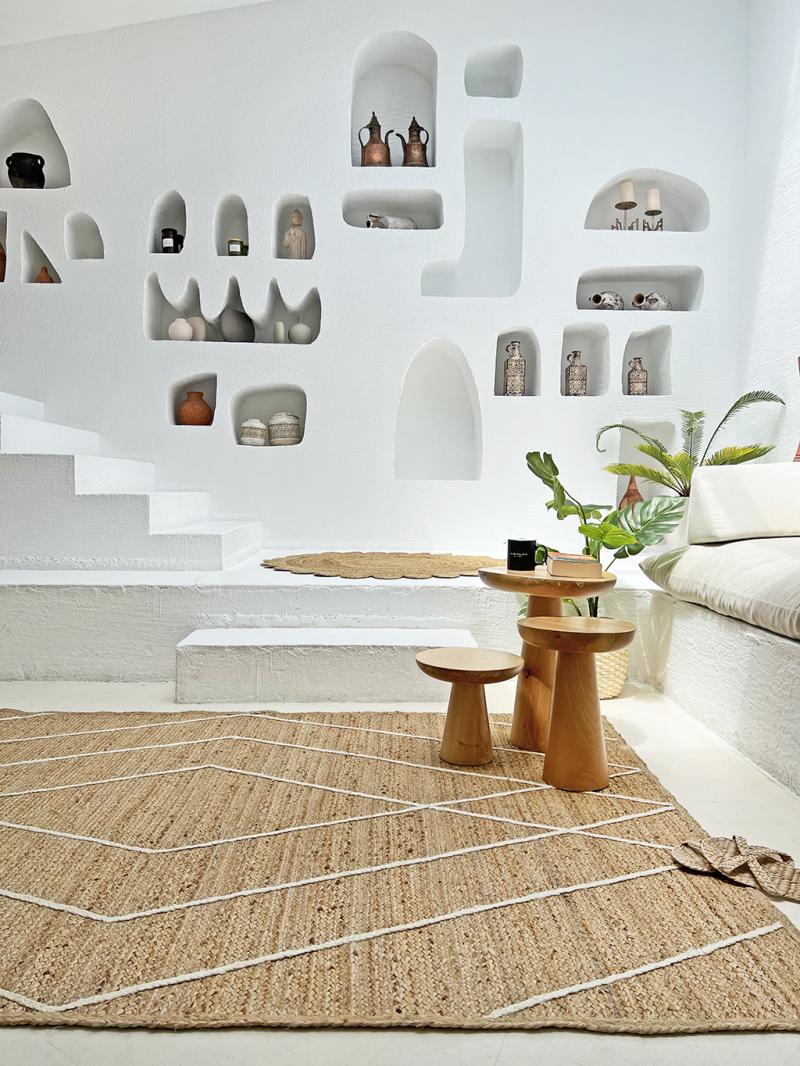 White wall niches displaying decor, wooden tables, jute rug with pattern