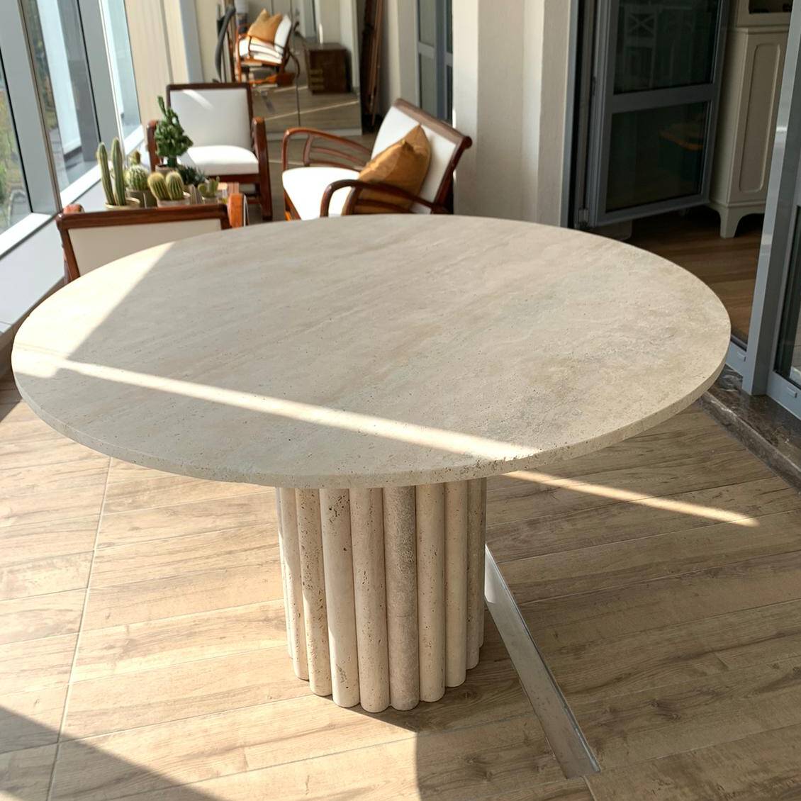 Close-up of the Luzione Freya round travertine dining table with cylindrical legs, perfect for modern balcony or patio dining