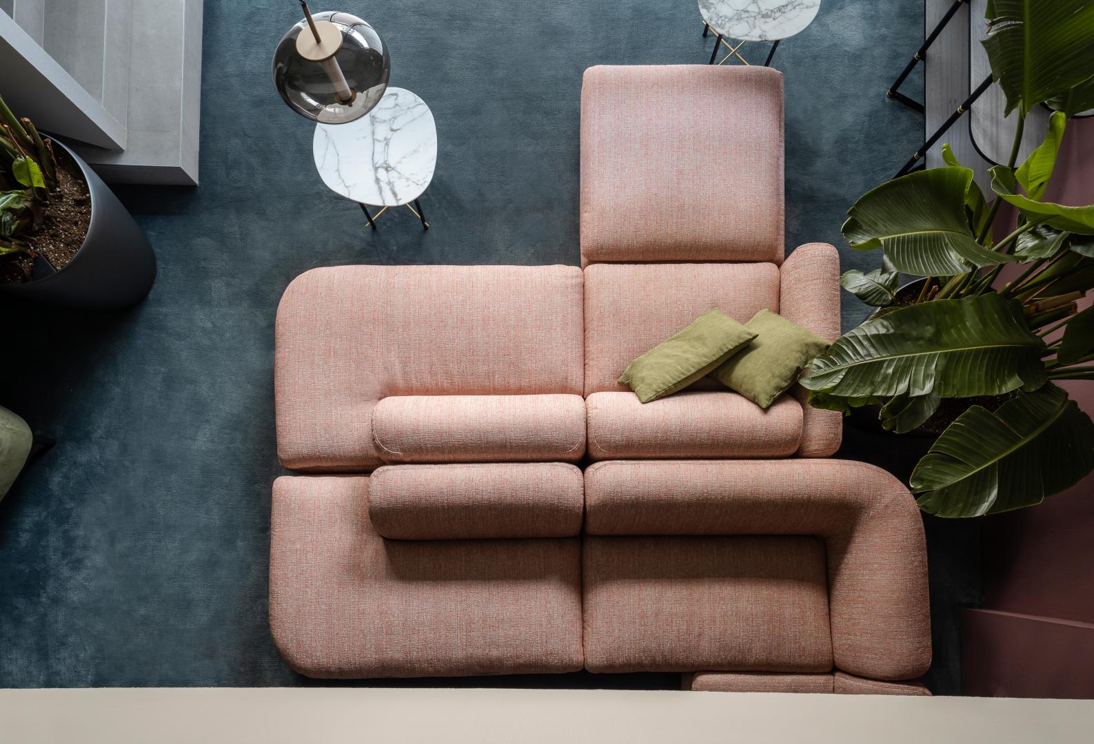 High-angle view of a modern living room featuring a pink Casamilano Botero modular sofa, green pillows, marble tables, and stylish decor
