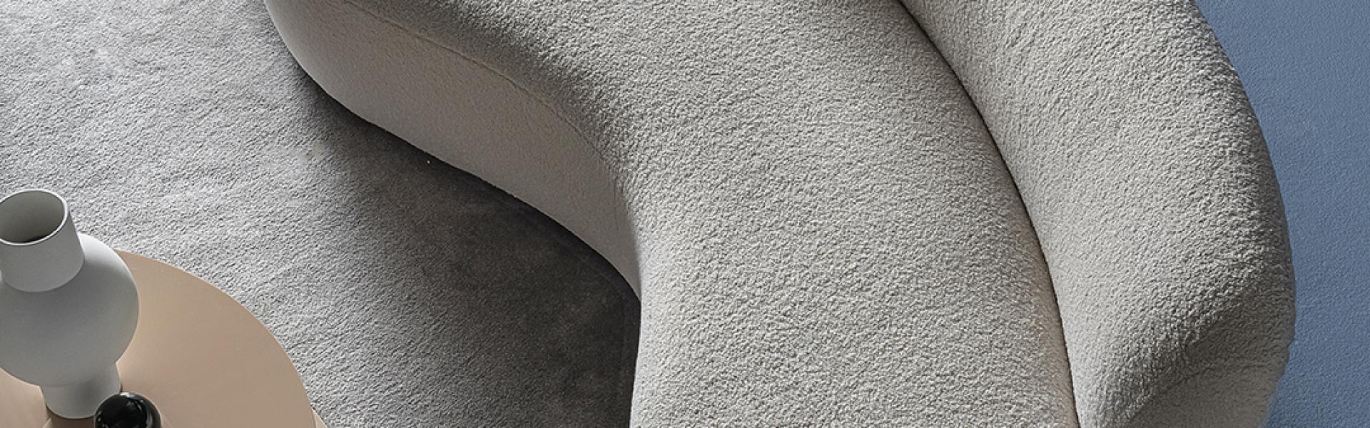 Close-up of Casamilano's Curvy Mono sofa in a modern living room with a light gray rug and round side table