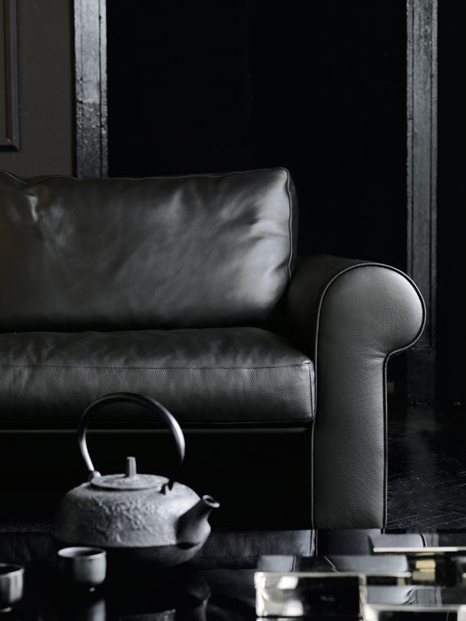 Black leather sofa armrest with cast iron teapot and teacups