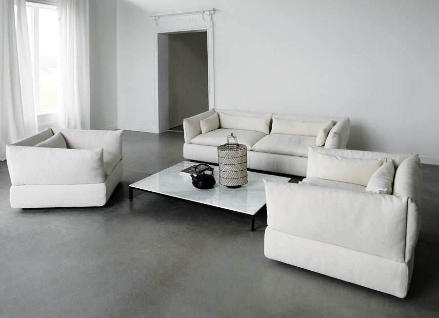 View of white sofa, two white armchairs, marble coffee table, lantern decor.