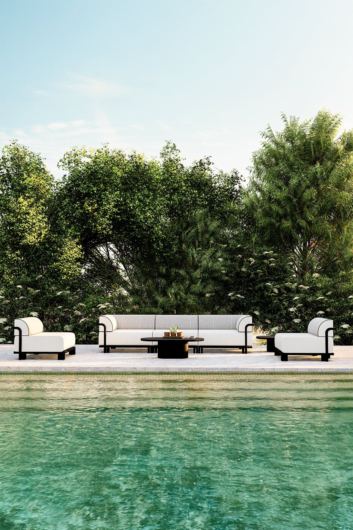Modern outdoor seating set with white cushions and black piping placed beside a pool, surrounded by greenery.