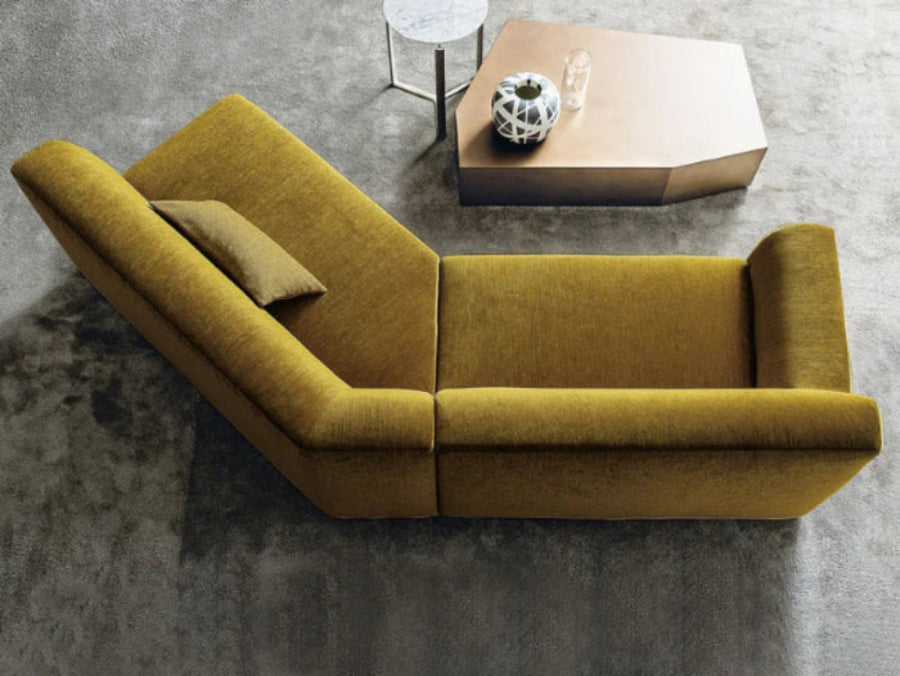 Yellow sectional sofa in a modern room with a brass coffee table and marble side table with decorative items.