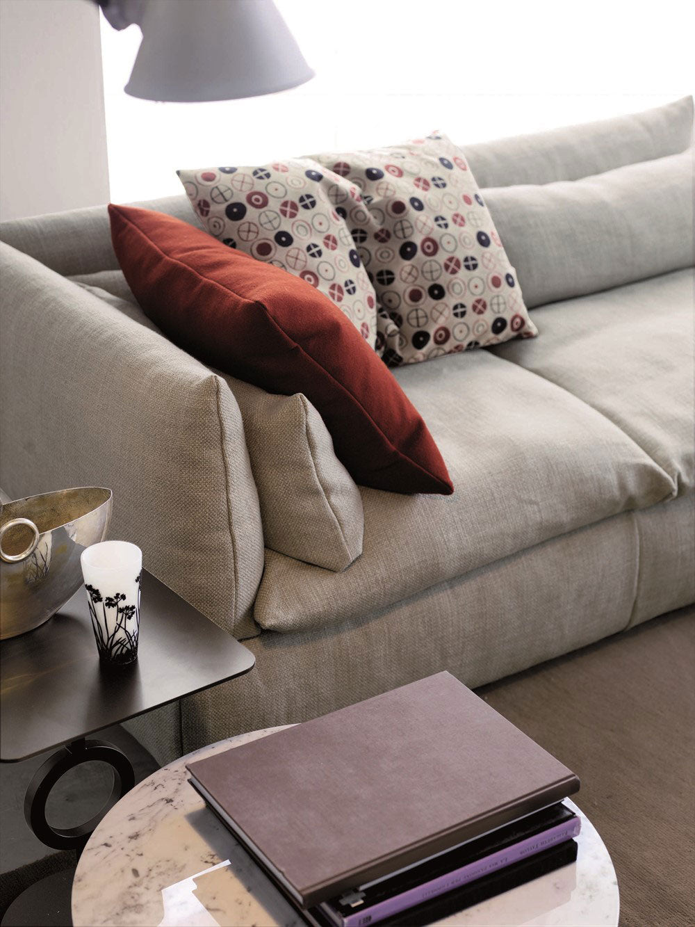 Close up view of gray fabric sofa with pillows and side tables.