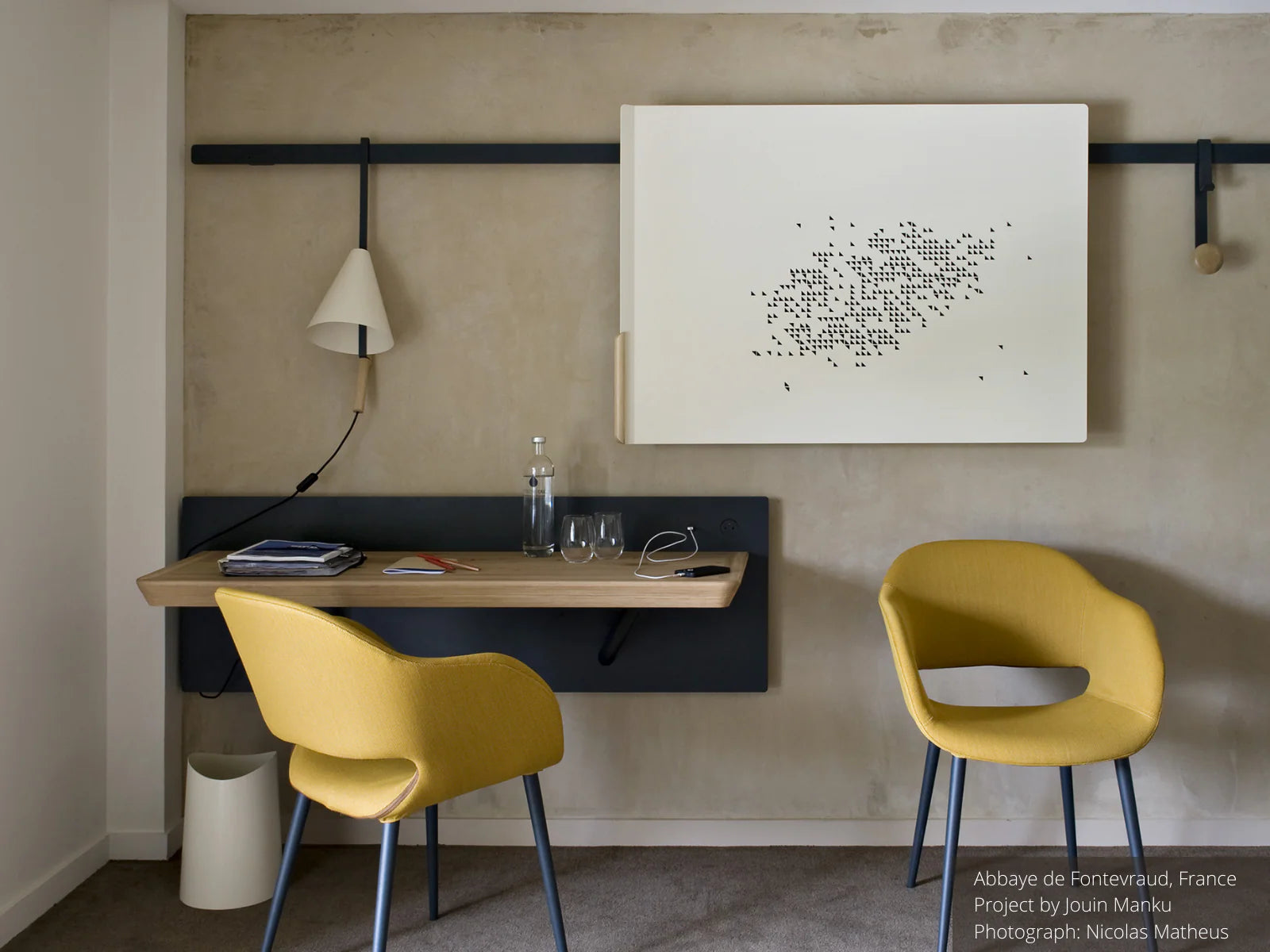 Hotel room desk area with yellow chairs, wall desk, and artwork.
