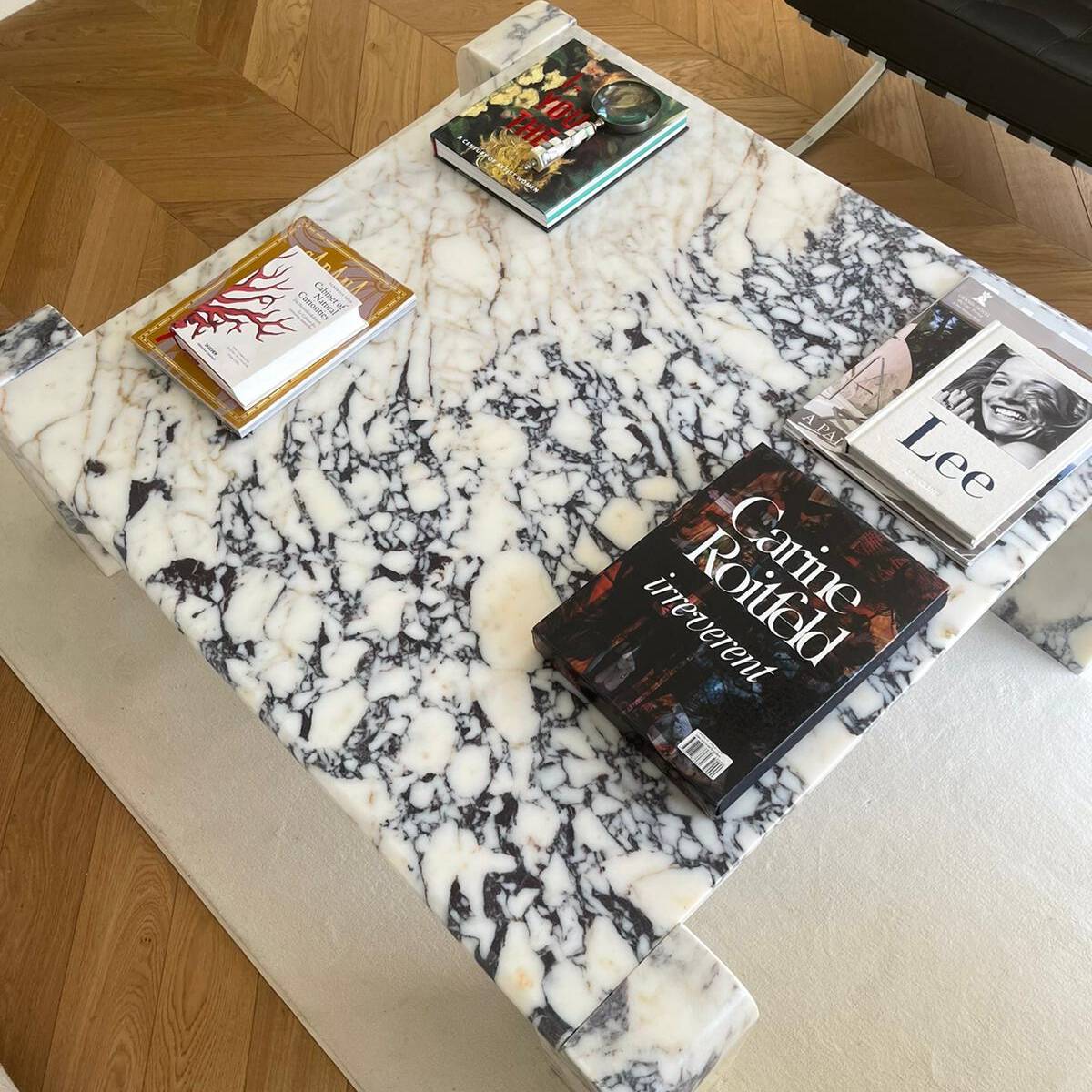 High-angle view of Luzione's square marble coffee table with art books. Blue and white marble add luxury to this modern living room centerpiece.