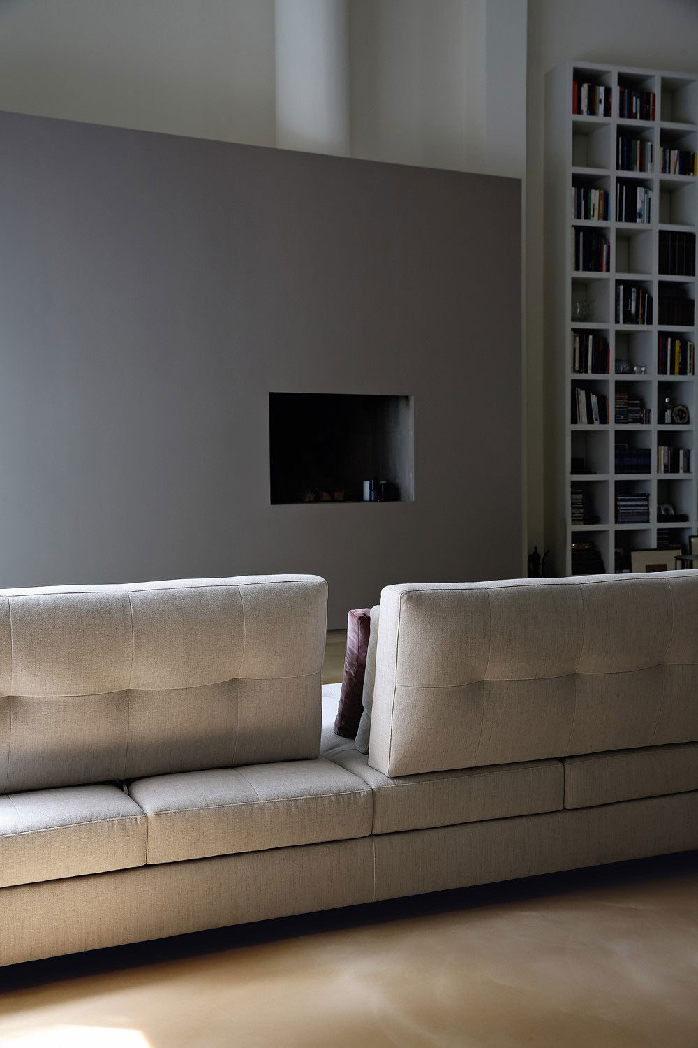 View of light beige sectional sofa backs, modern fireplace niche.