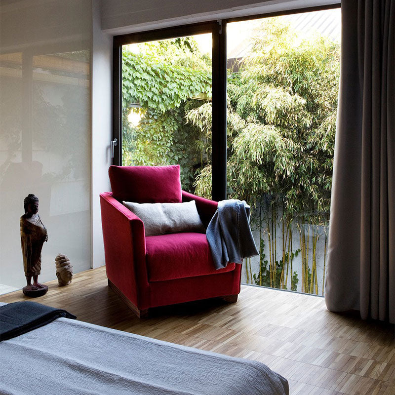 bedroom view with red armchair, wood floor, window, bamboo garden