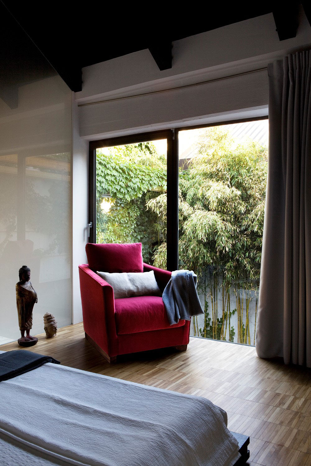 bedroom view with red armchair, bed, window, and wood floor