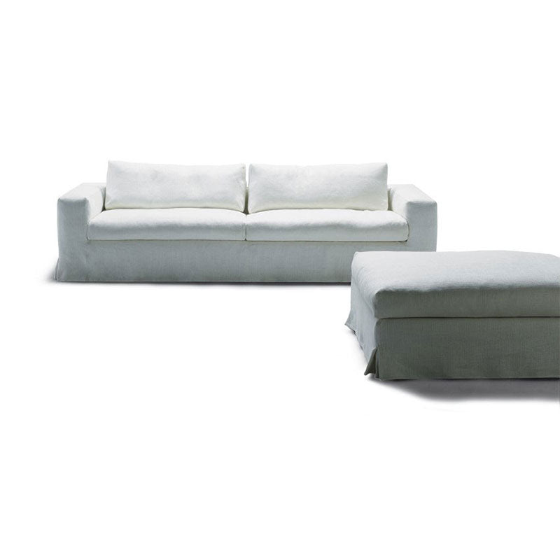 White fabric sofa and ottoman with slipcovers against white background