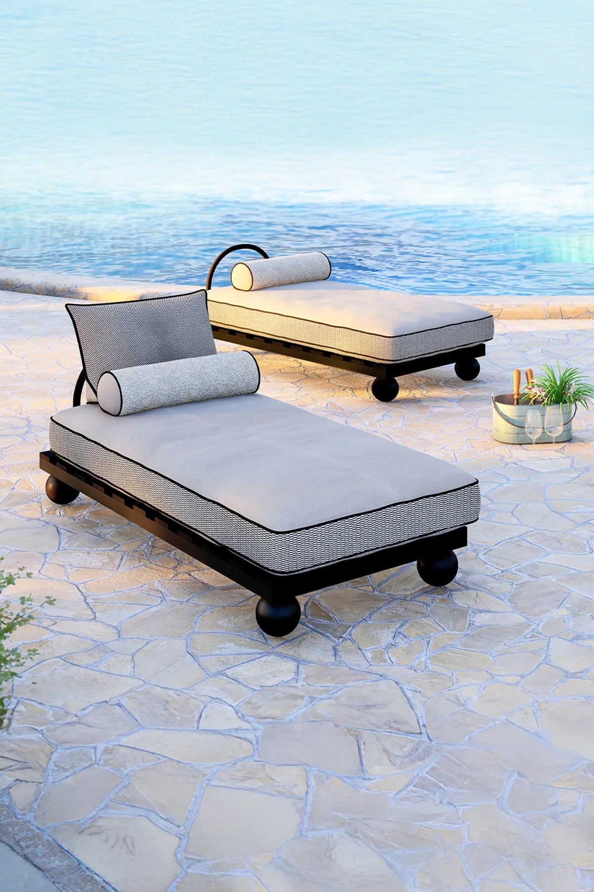 Two outdoor lounge chairs on a stone patio with ocean view