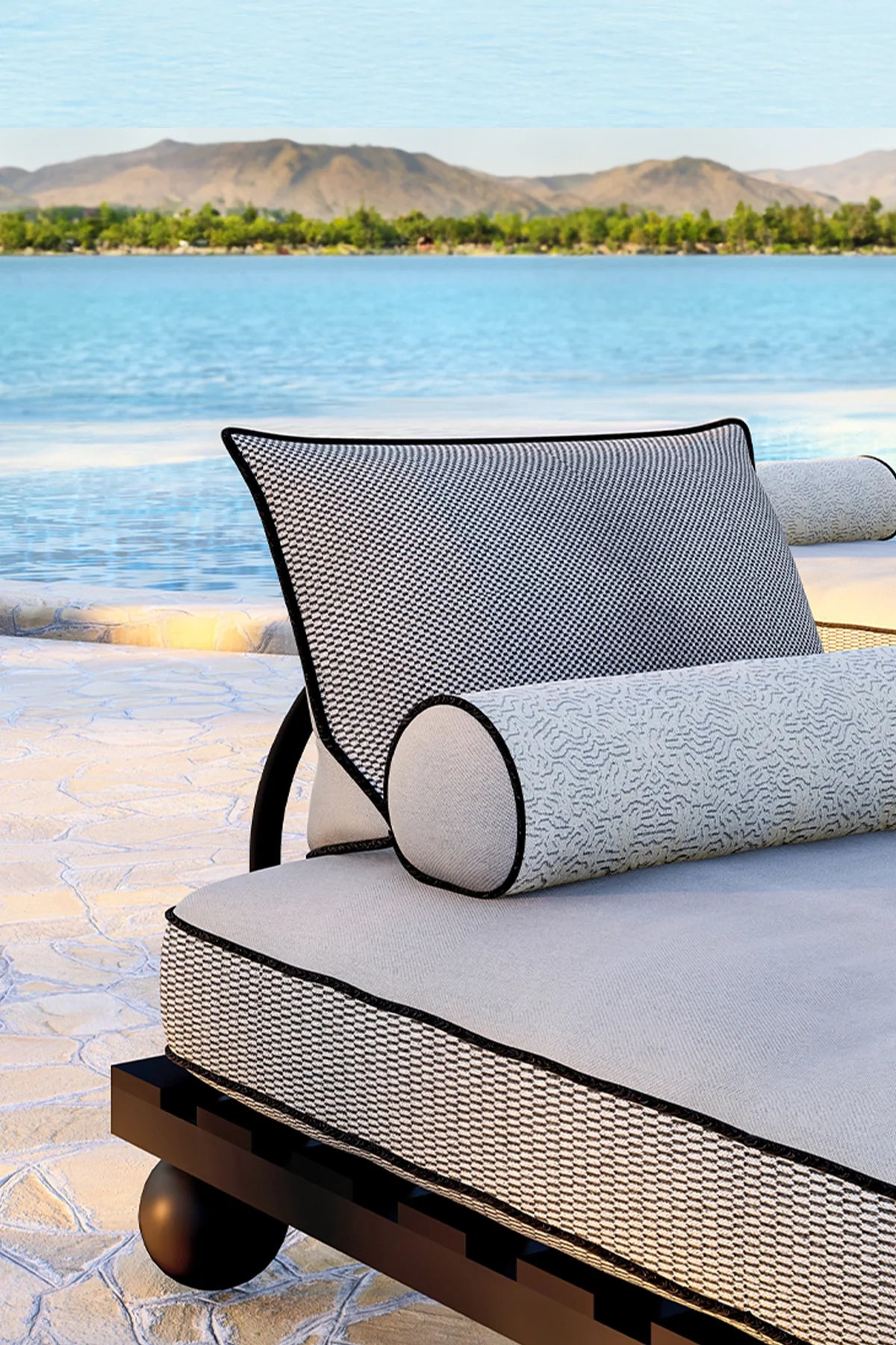 Black-finished outdoor daybed with iroko wood frame and metal backrest, styled beside a pool with neutral cushions.