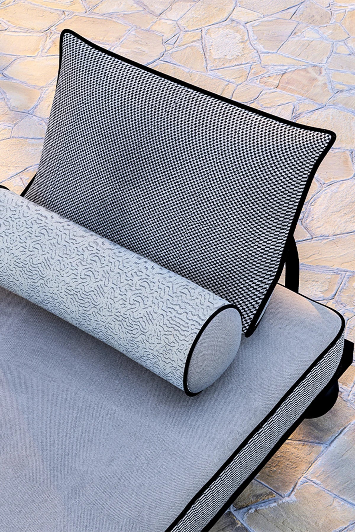 Gray cushion with textured surface and black mesh backrest on a stone pavement background