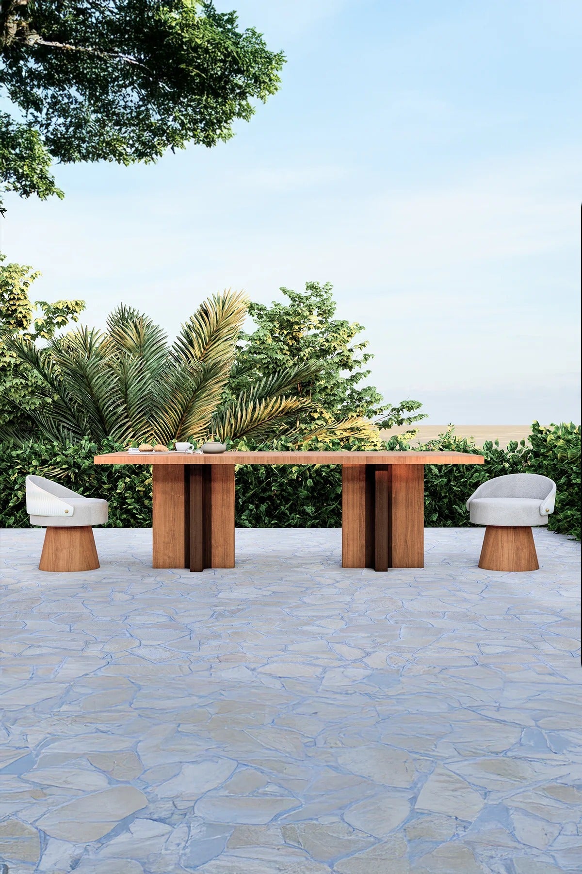 Outdoor setting with a wooden table and chairs on a stone patio, surrounded by greenery.