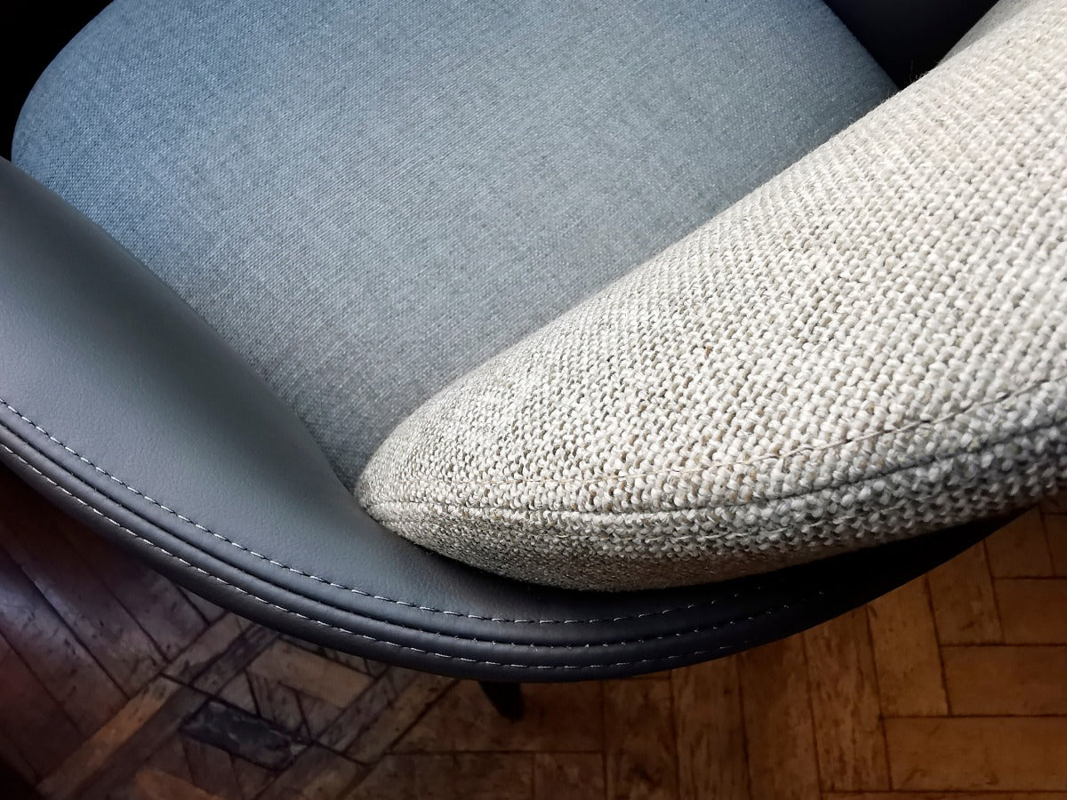 Overhead view of gray leather chair with fabric cushion and pillow on wood floor
