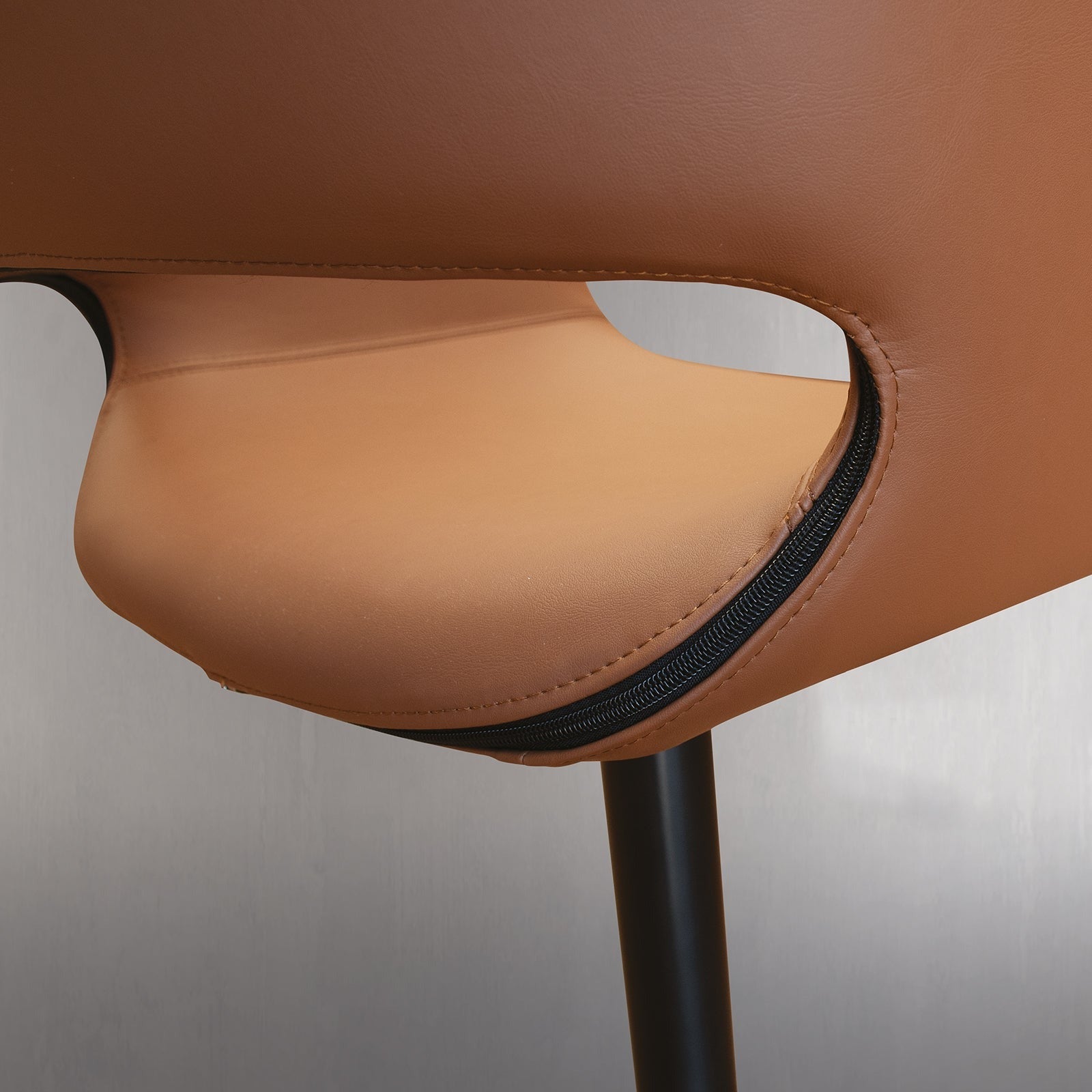 Close up of brown leather chair with black zipper detail