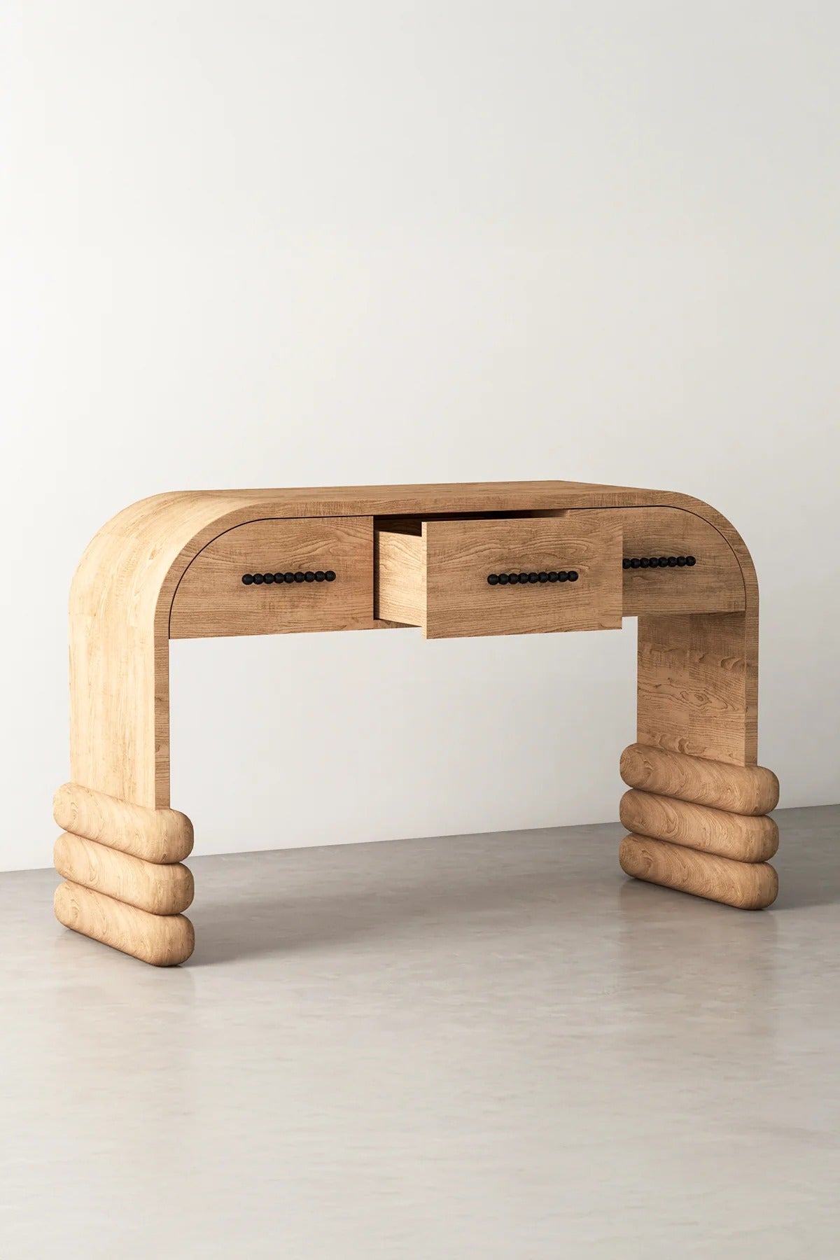 Light wood console table with three drawers, one open.