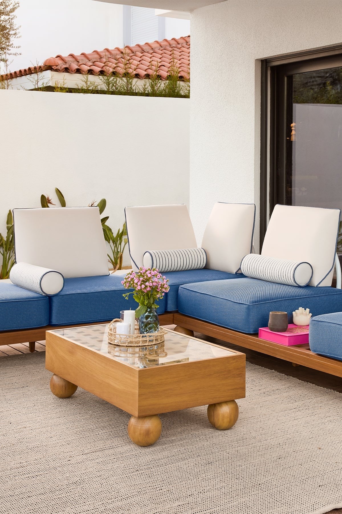 Outdoor patio with blue sectional sofa, wooden coffee table, and decorative items.