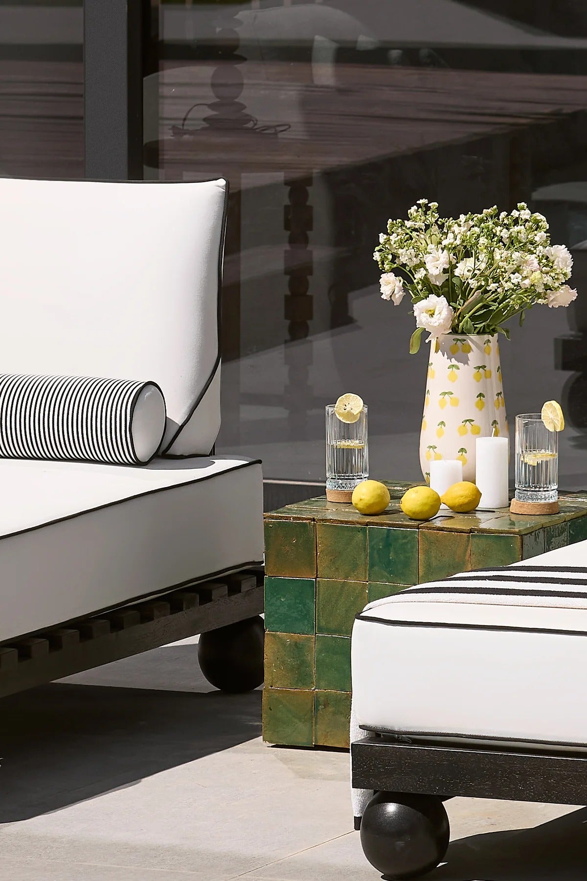 Outdoor furniture set with a table, chairs, and decorative items on a reflective surface.