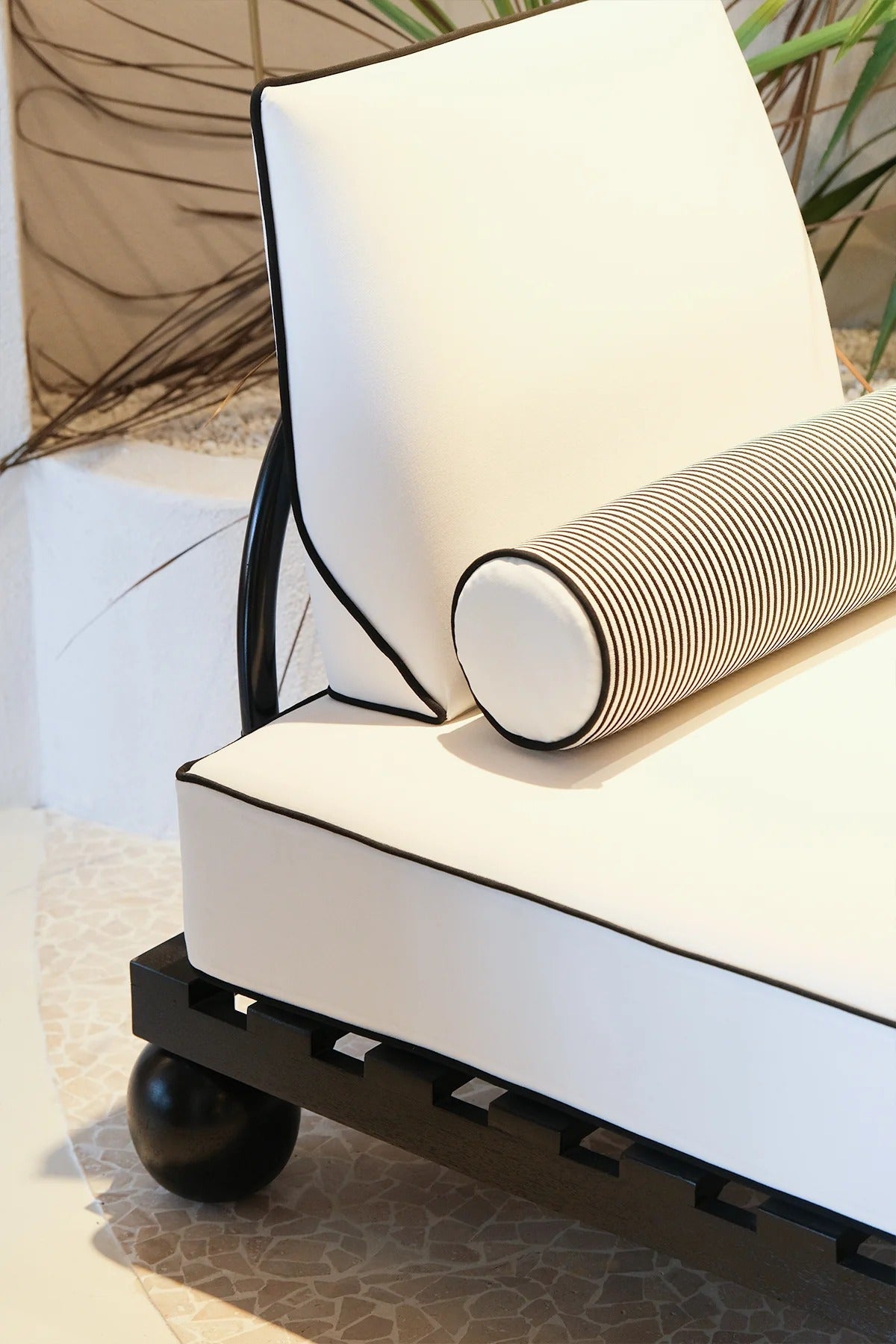 Modern outdoor chair with white cushion and black metal frame on a patio.